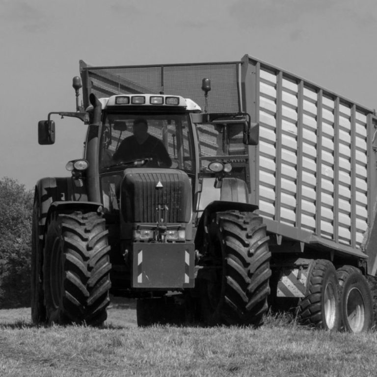Traktor Ein großer, grüner Traktor zieht einen Anhänger über ein Feld.